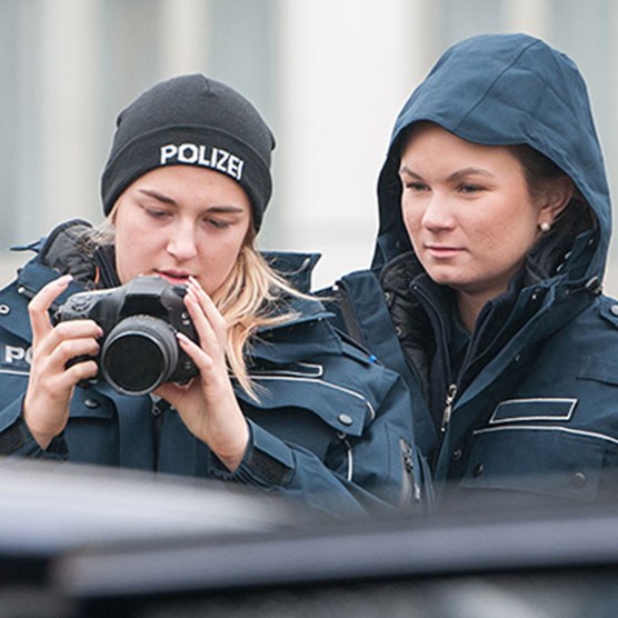 Zwei Polizistinnen dokumentieren fotografisch ein Beweismittel.